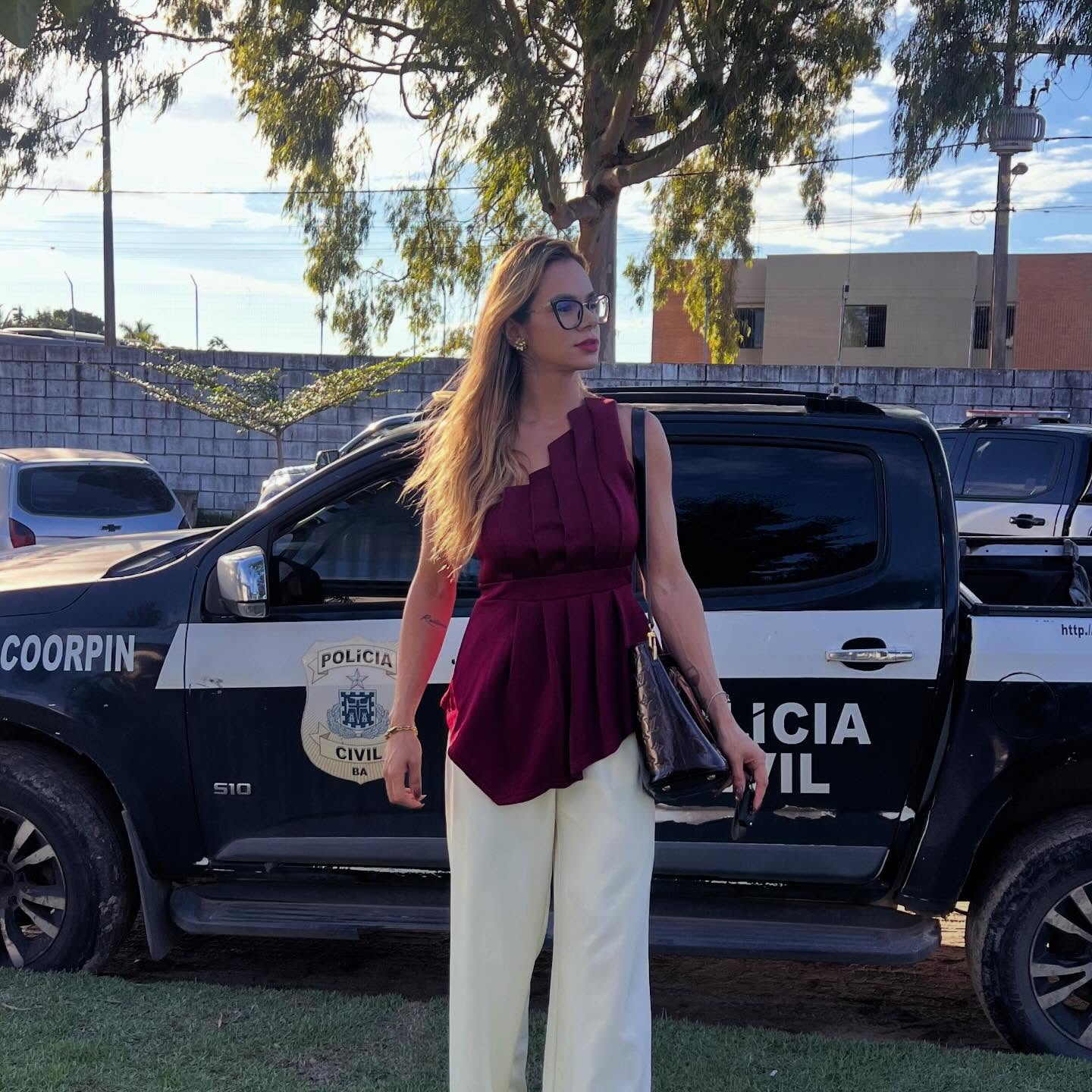 Dra. Gabriela Bruny em frente a uma viatura policial