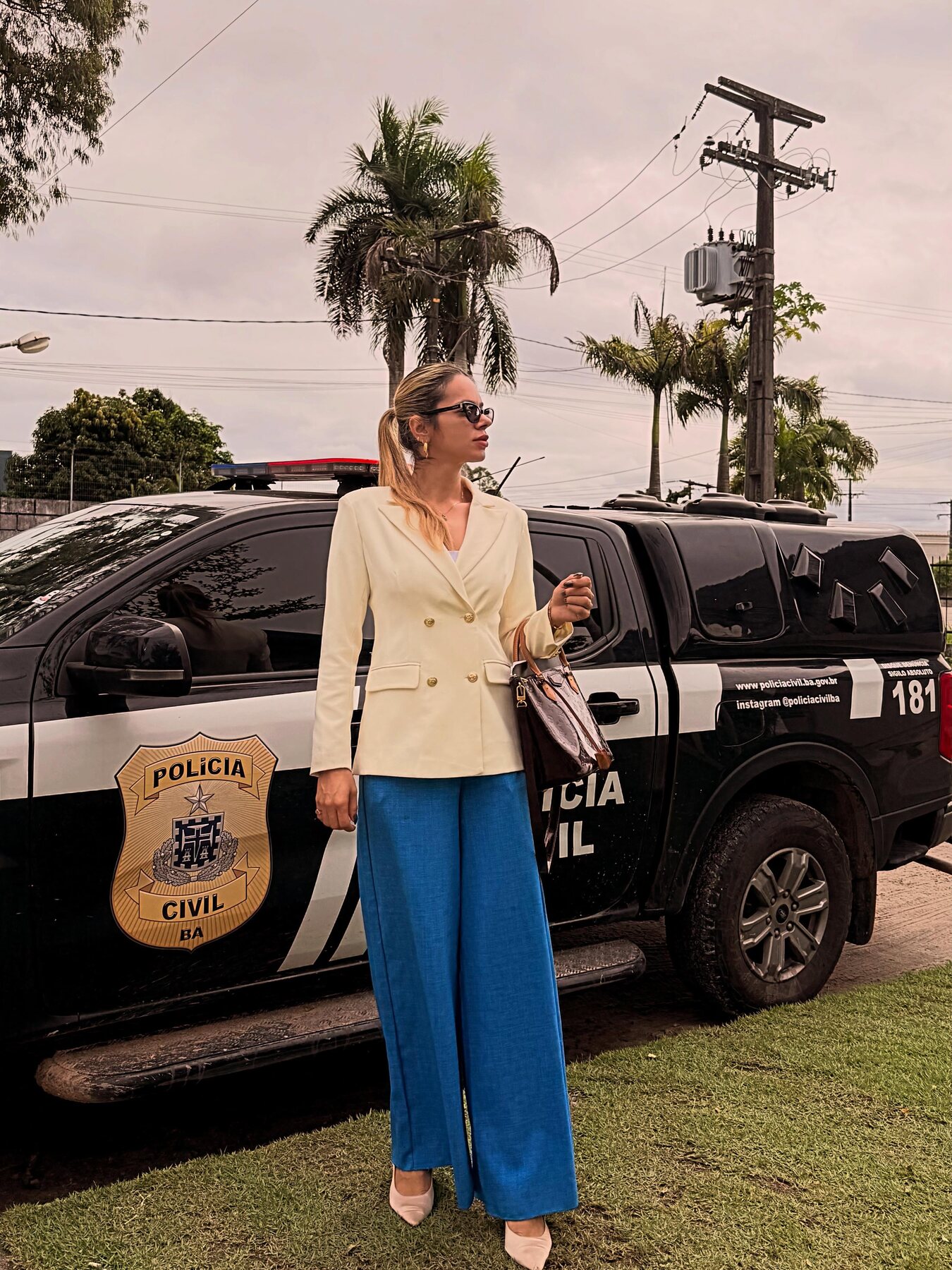 Dra. Gabriela Bruny em frente a uma viatura da Polícia Civil